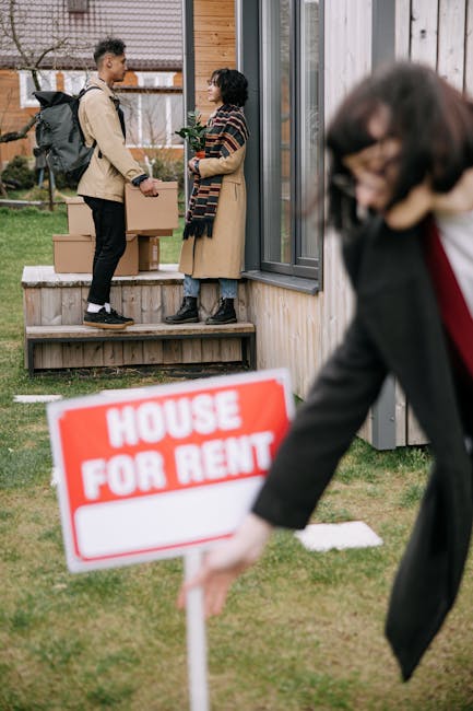 Two individuals are engaged in a conversation outside a residential property, with one holding a house key and a cardboard box, indicating a move-in or move-out scenario. The property features a wooden exterior, large glass windows, and a small porch, with natural daylight illuminating the scene. In the foreground, a person dressed in business attire is reaching for a red and white 'House For Rent' sign, slightly blurred to emphasize the focus on the conversation between the two people at the door. This image reflects a typical end-of-tenancy or rental process, highlighting the importance of professional cleaning services from companies like Cleaners Kennington to ensure properties are left in pristine condition for new tenants or owners.