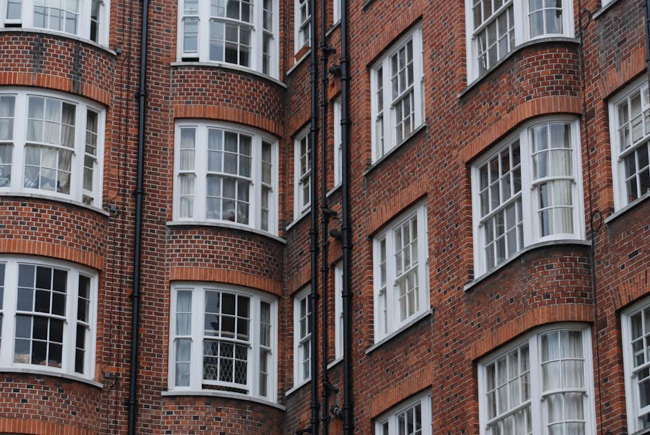 Close-up view of the exterior brick façade of a multi-story residential building in Kennington, featuring multiple white-framed sash windows curved outward with decorative arches. The brick surface i