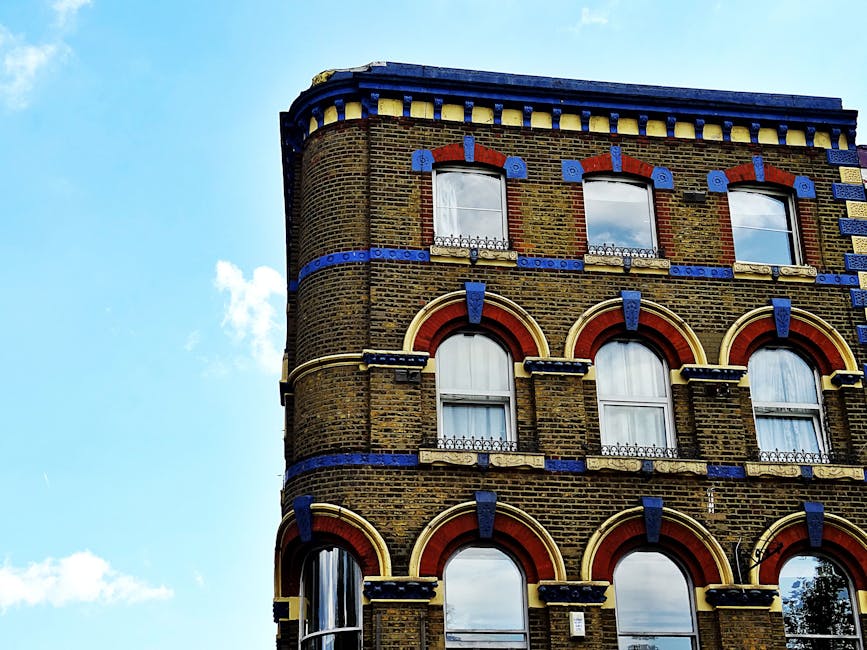 Close-up view of the exterior brick façade of a multi-story residential building in Kennington, featuring multiple white-framed sash windows curved outward with decorative arches. The brick surface i